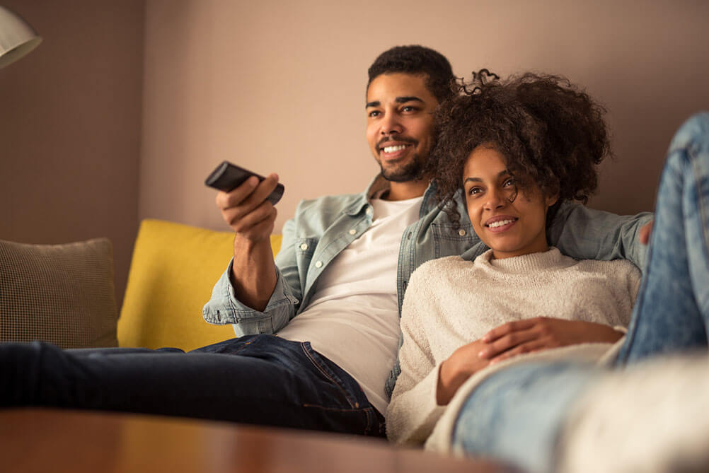 Lottery Winning Numbers from TV shows and Movies A smiling couple watch TV from their sofa