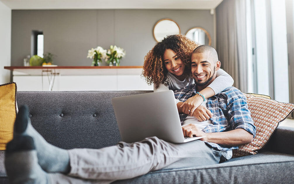 Happy couple on sofa with laptop 