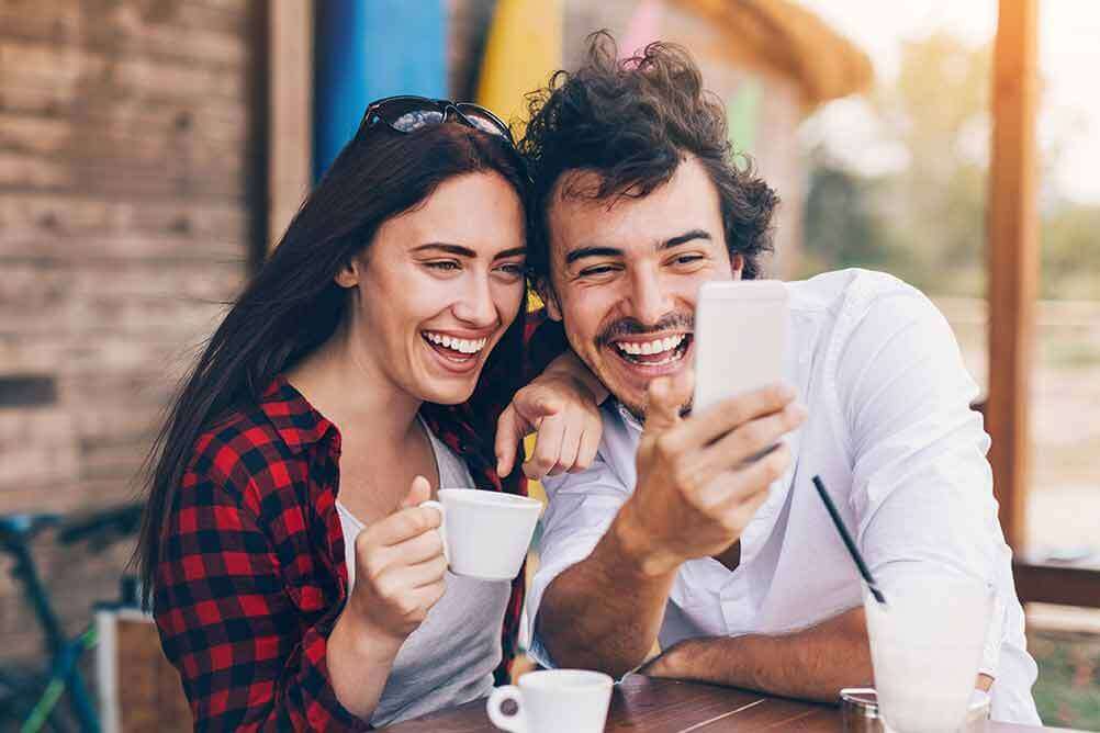 Laughing couple betting on EuroJackpot online with their smartphone