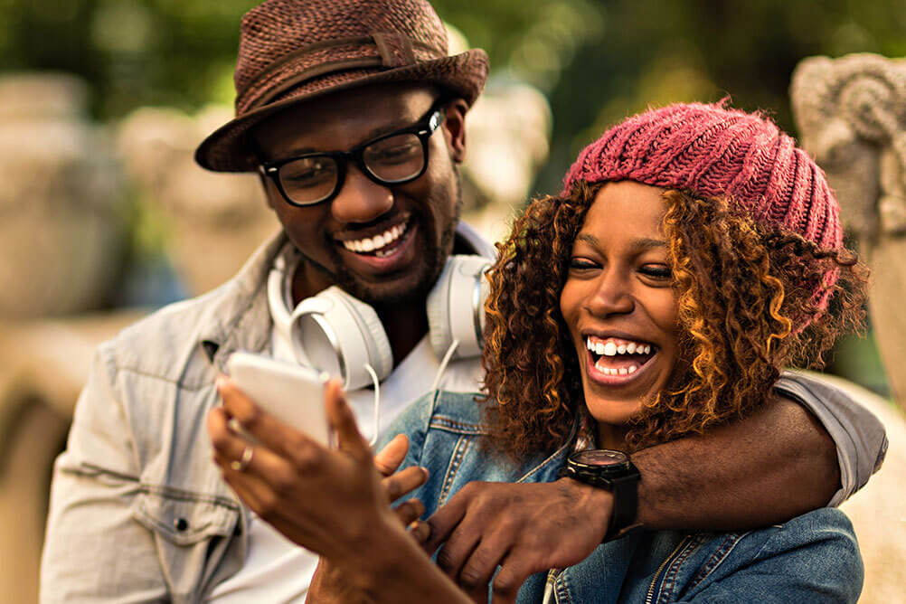 Happy couple checking their phone after registering at Lottoland South Africa