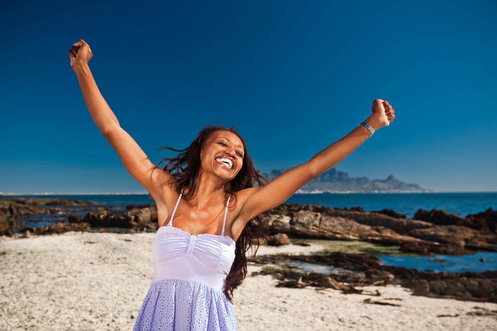 South African woman on beach celebrating biggest SA lotto win