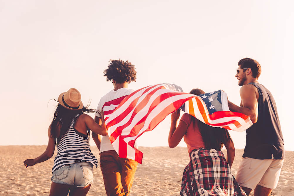 group-of-friends-running-on-beach-with-american-flag