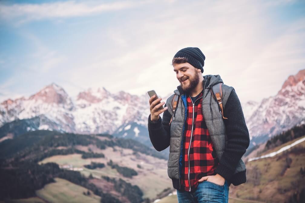 A man, on his phone in the Austrian Alps, learning how to bet on the Austria Lotto
